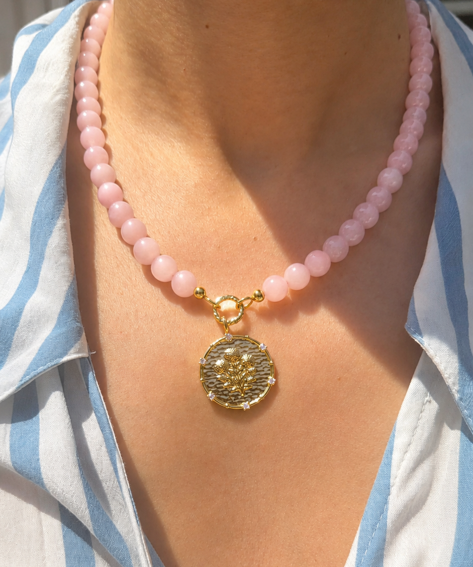 pink rose quartz beaded necklace with a coin pendant with a floral motif