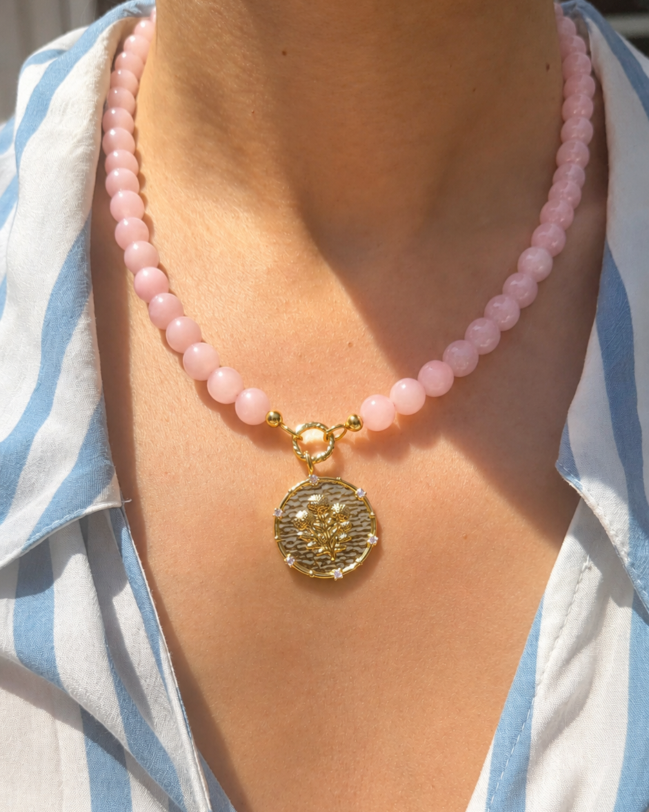 pink rose quartz beaded necklace with a coin pendant with a floral motif