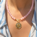 pink rose quartz beaded necklace with a coin pendant with a floral motif