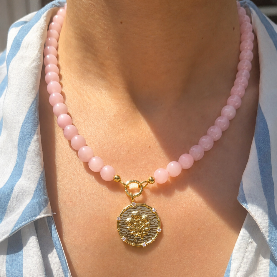 pink rose quartz beaded necklace with a coin pendant with a floral motif