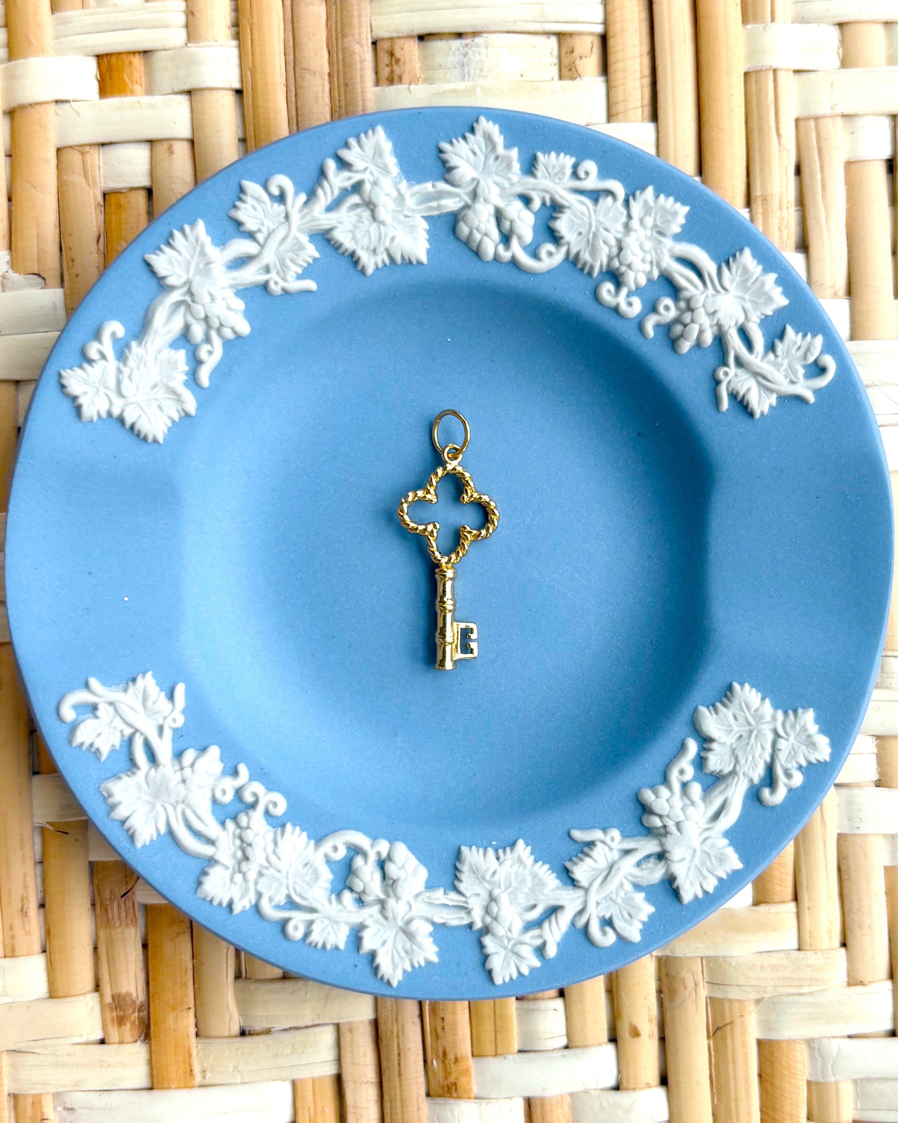 Decorative blue plate with white floral patterns and a golden key charm on a woven mat background
