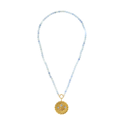 gold scalloped charm with blue gemstones on an aquamarine stone strand of beads