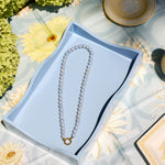 light blue beaded necklace with a gold clasp on a blue tray 