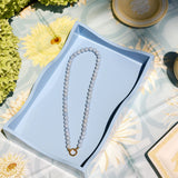 light blue beaded necklace with a gold clasp on a blue tray 