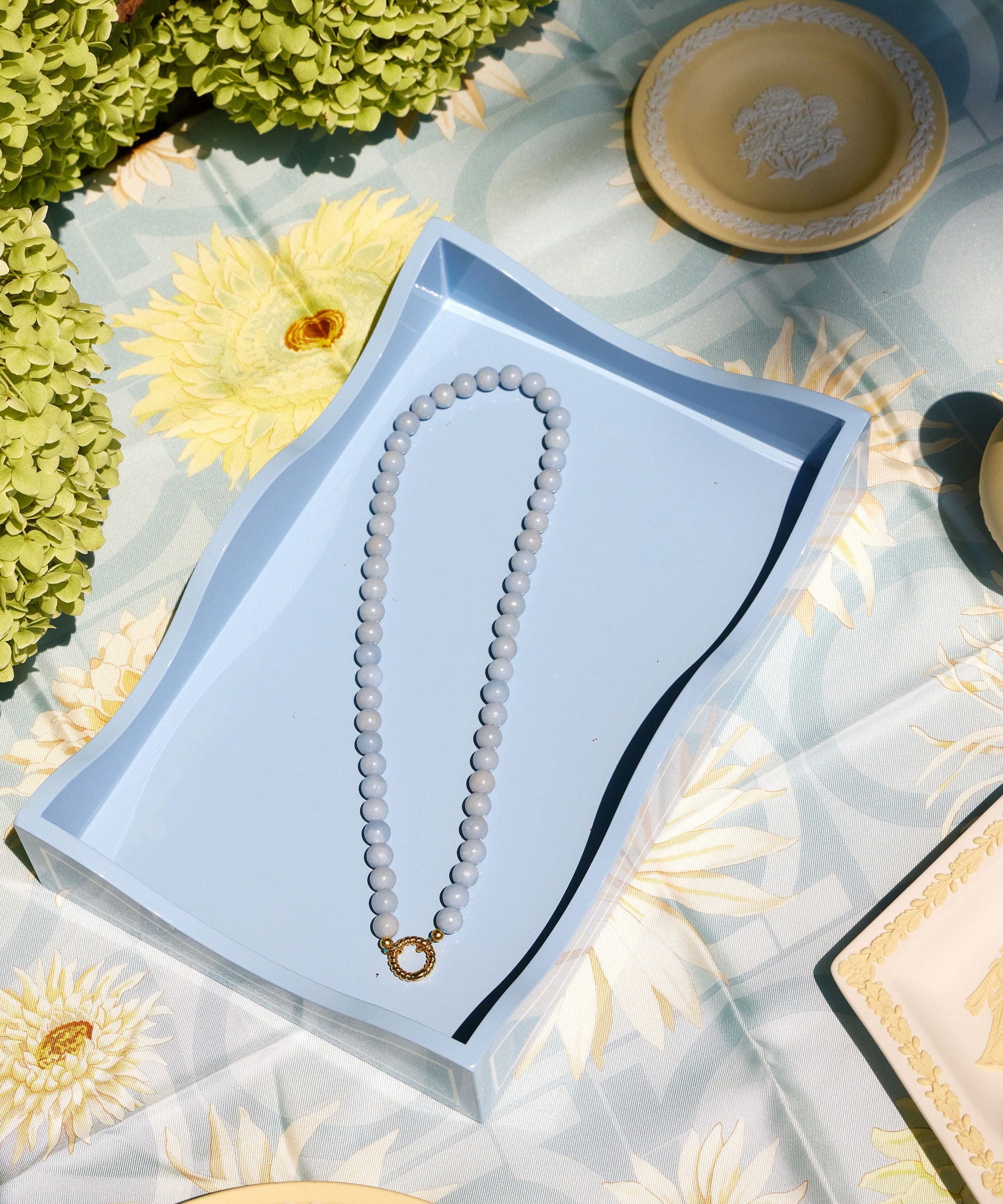 light blue beaded necklace with a gold clasp on a blue tray 