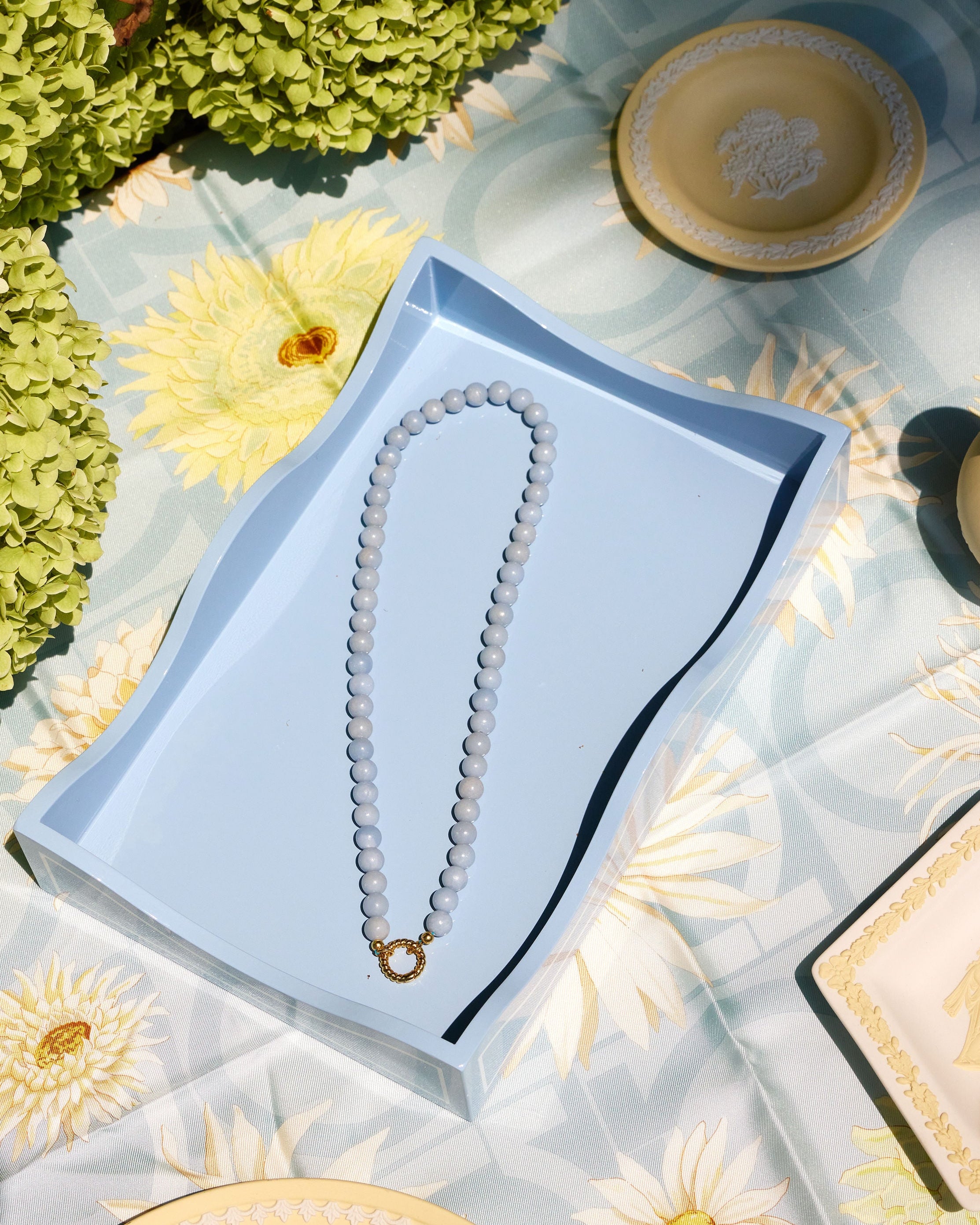 light blue beaded necklace with a gold clasp on a blue tray 