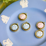 cameo pendant charms displayed on a blue plate with a flower in the background