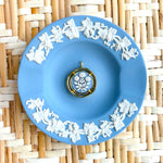 Blue decorative plate with white floral patterns on a woven mat background displaying a blue and white cameo pendant