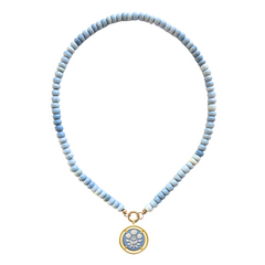 Necklace with light blue beads and a gold and blue cameo pendant on a white background