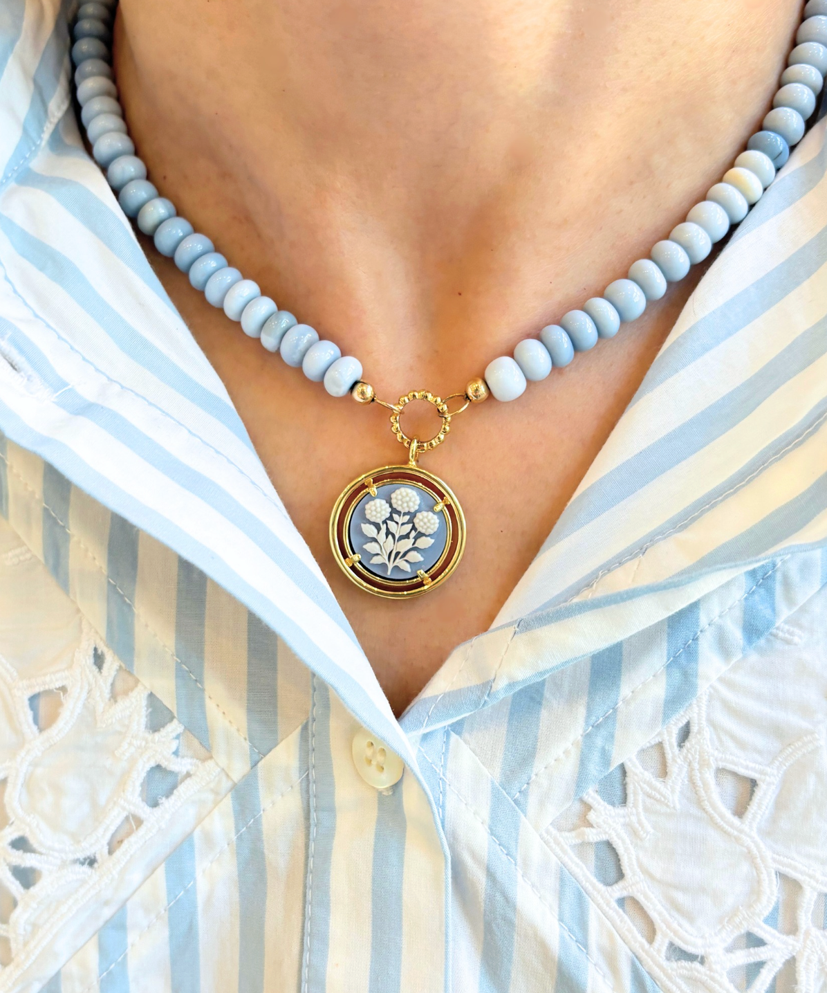 Necklace with a floral pendant worn by a person in a striped shirt
