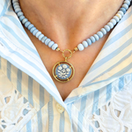 Necklace with a floral pendant worn by a person in a striped shirt