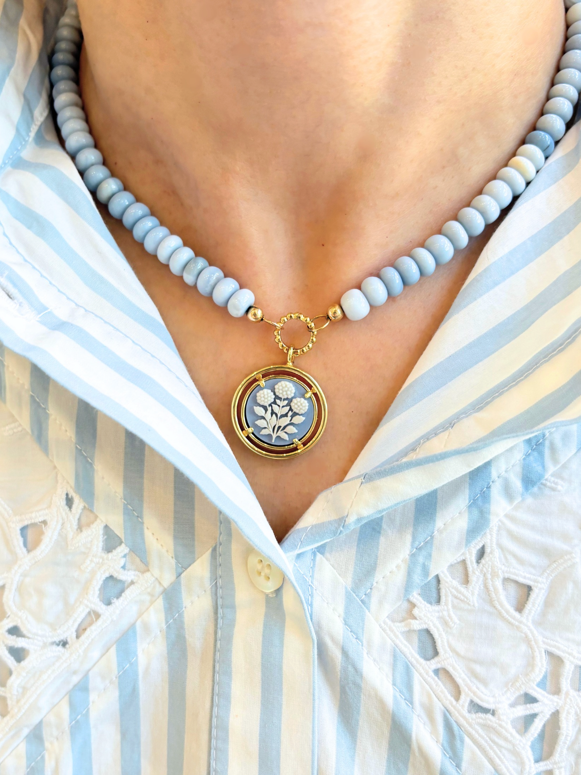 Necklace with a floral pendant worn by a person in a striped shirt