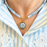 Necklace with a floral pendant worn by a person in a striped shirt