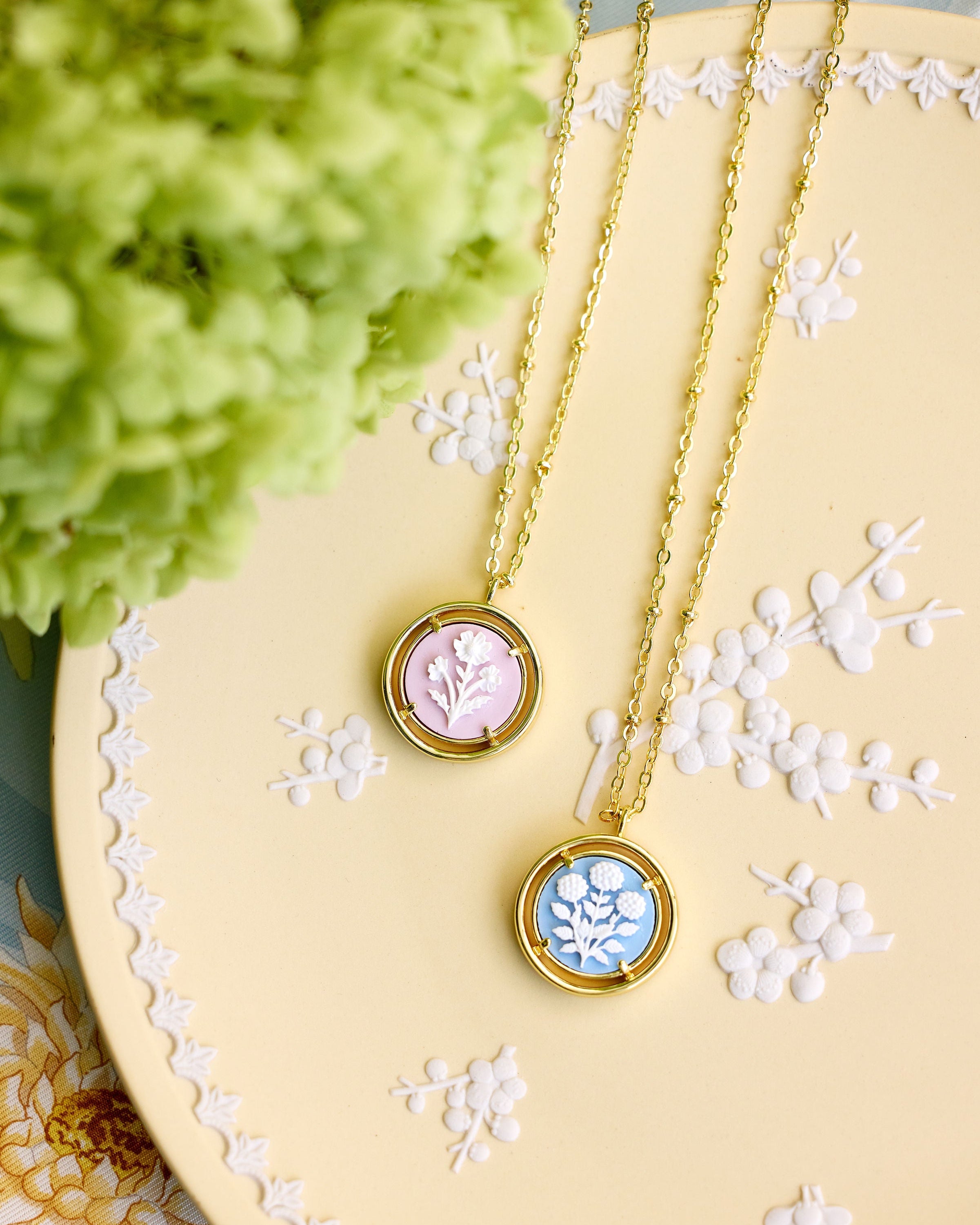 two cameo necklaces displayed on a light yellow plate
