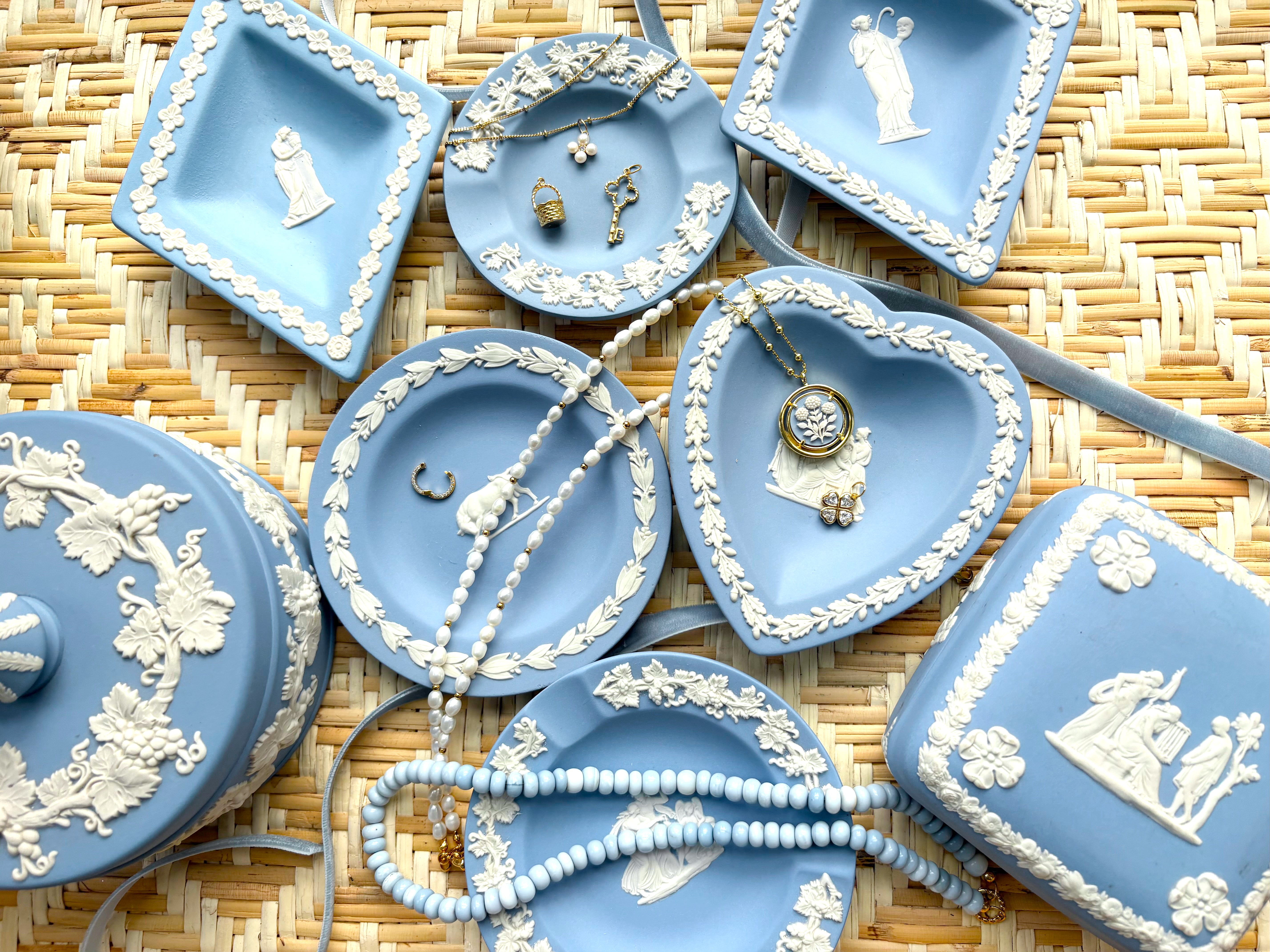 Collection of blue decorative plates with jewelry and charms on a woven surface
