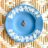 Blue decorative plate with a clover charm displayed on a woven background