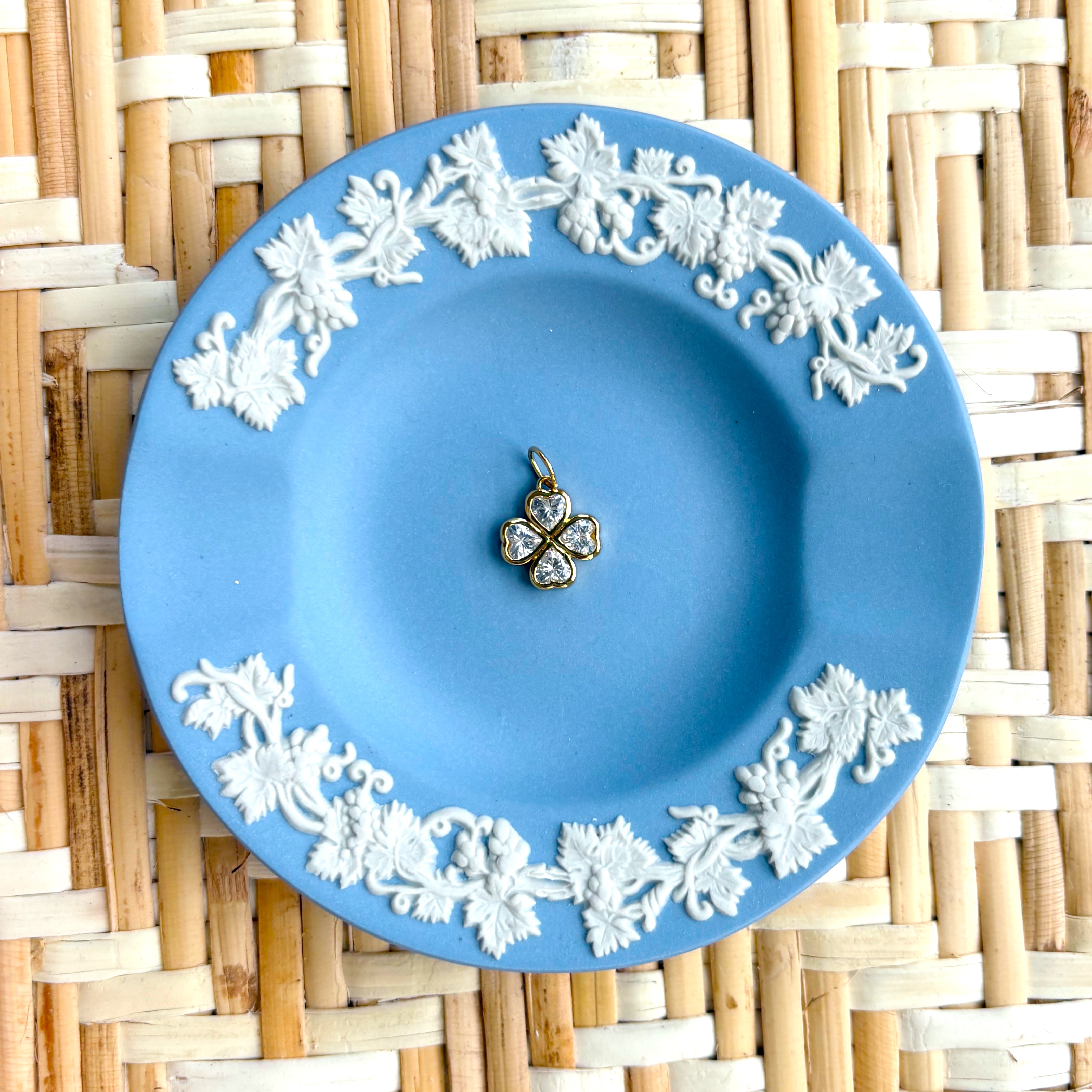 Blue decorative plate with a clover charm displayed on a woven background