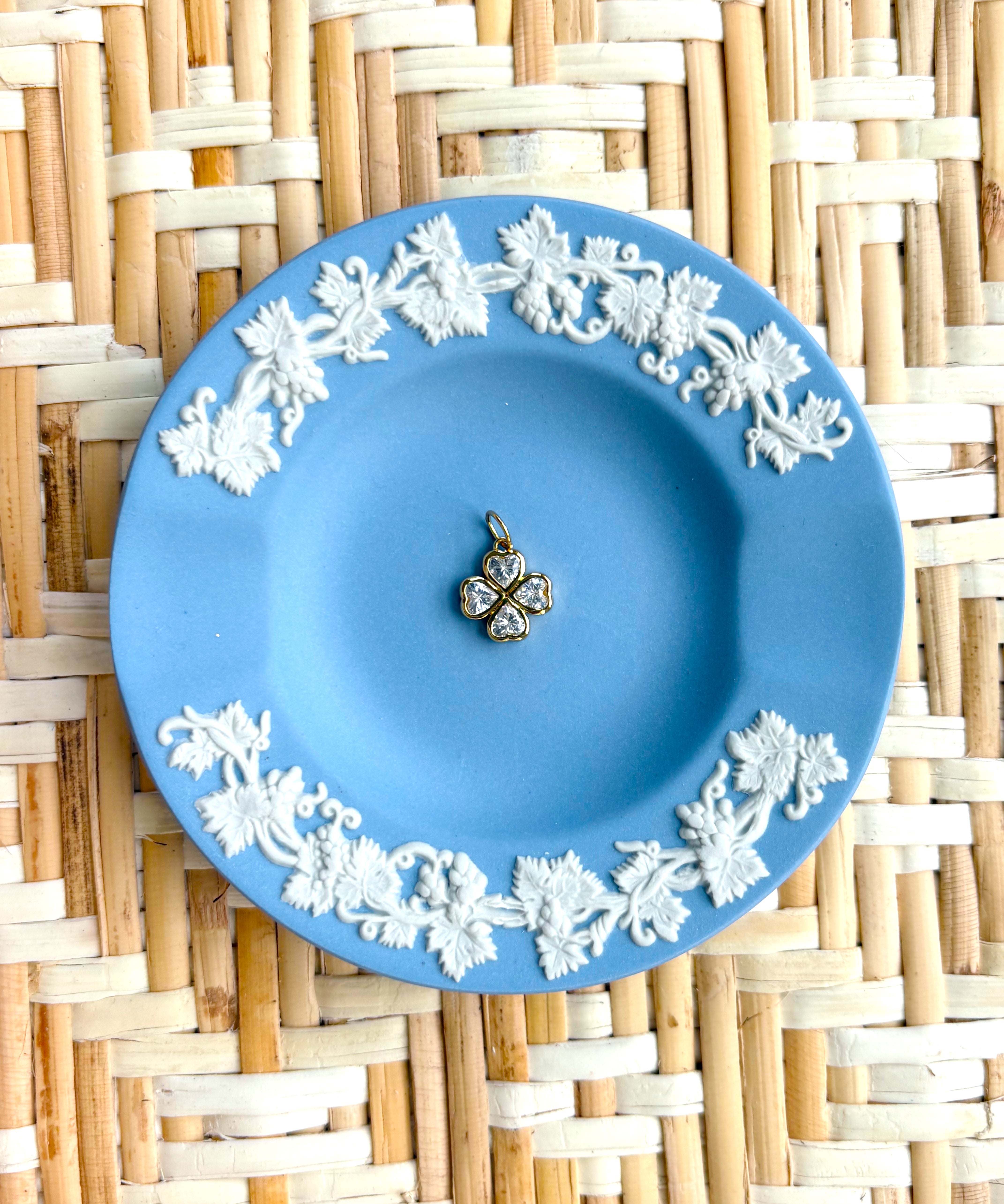 Blue decorative plate with a clover charm displayed on a woven background