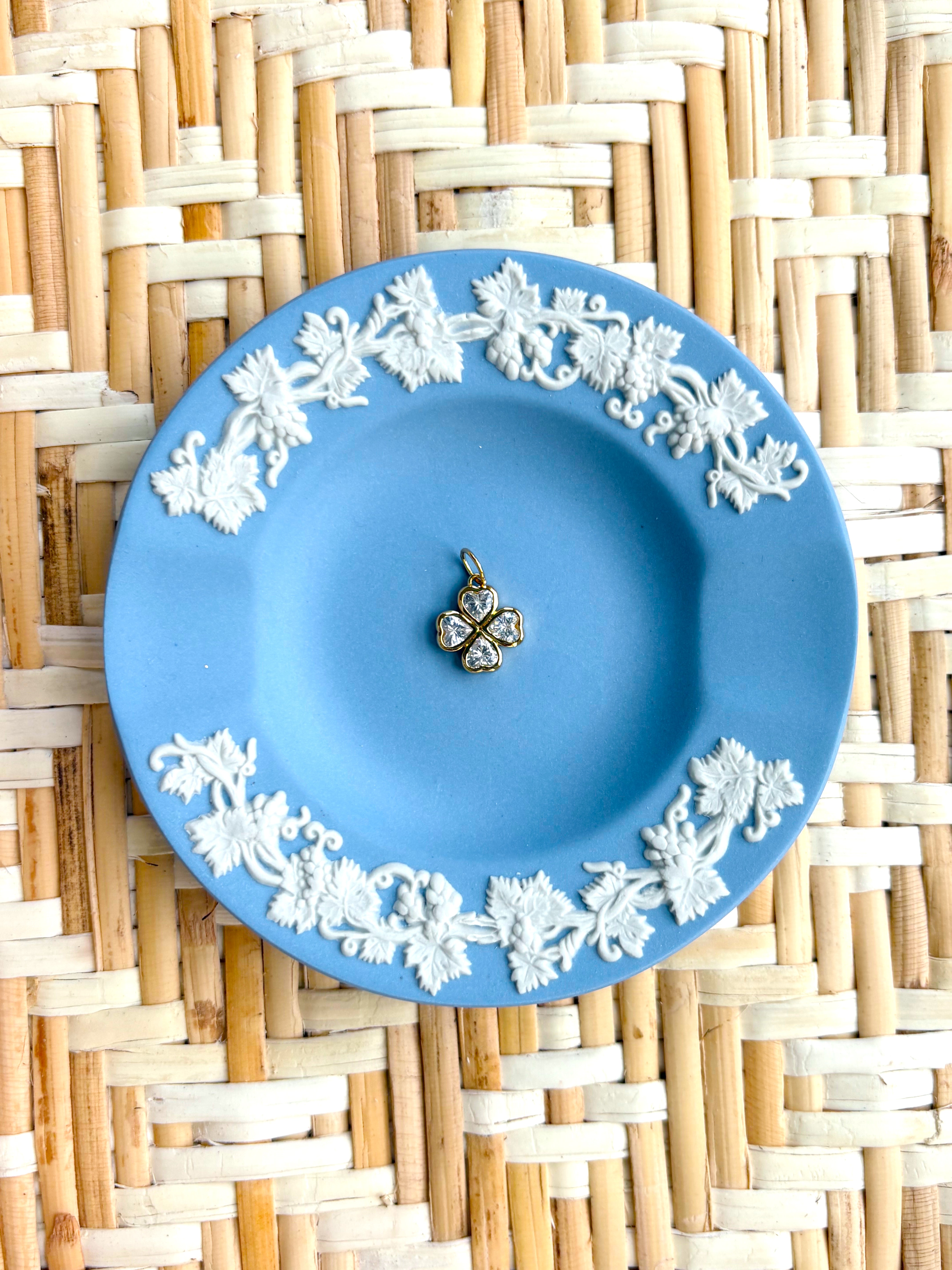 Blue decorative plate with a clover charm displayed on a woven background