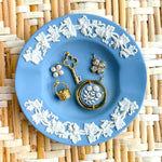 Jewelry set on a blue decorative plate with floral patterns on a woven mat background