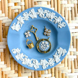 Jewelry set on a blue decorative plate with floral patterns on a woven mat background