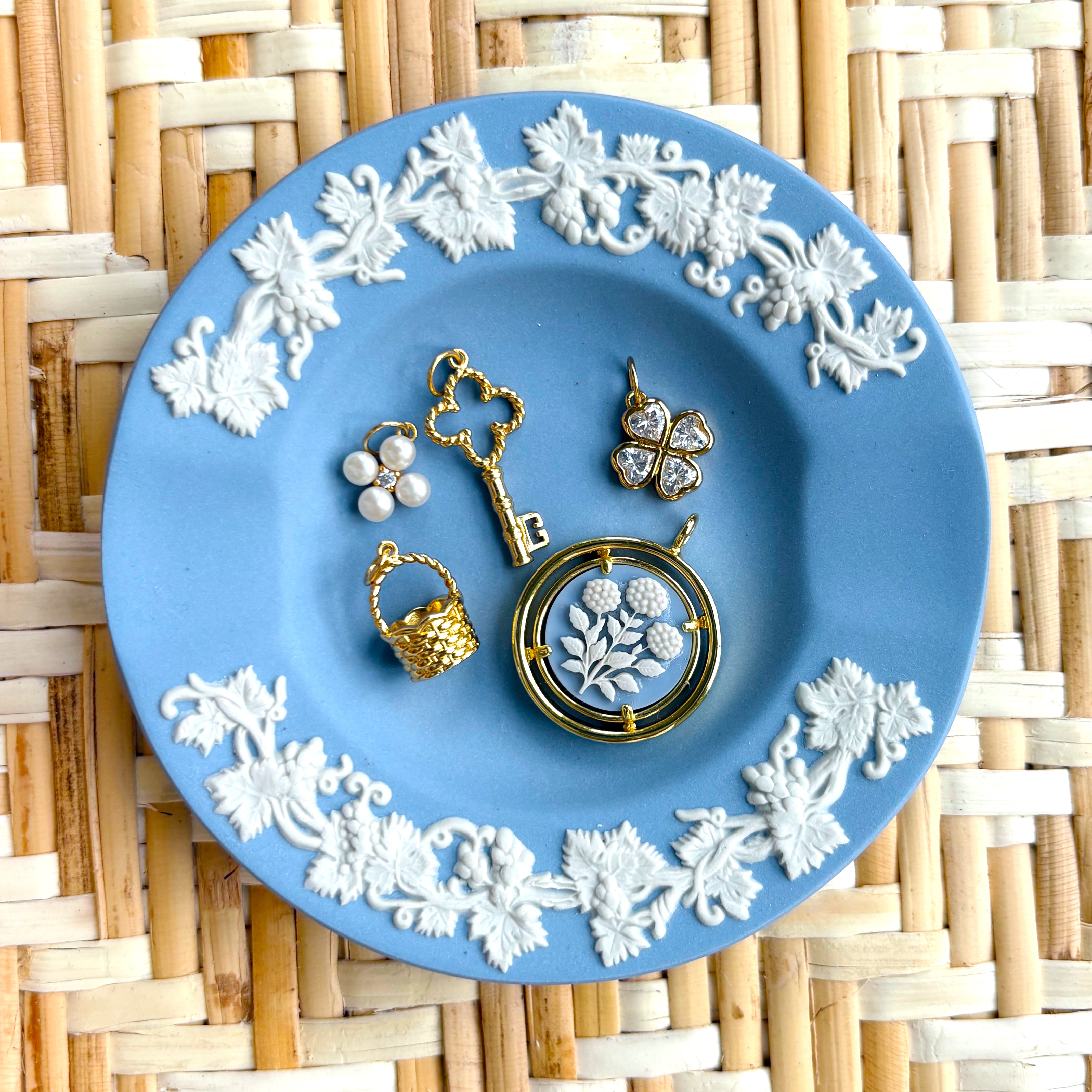 Jewelry set on a blue decorative plate with floral patterns on a woven mat background