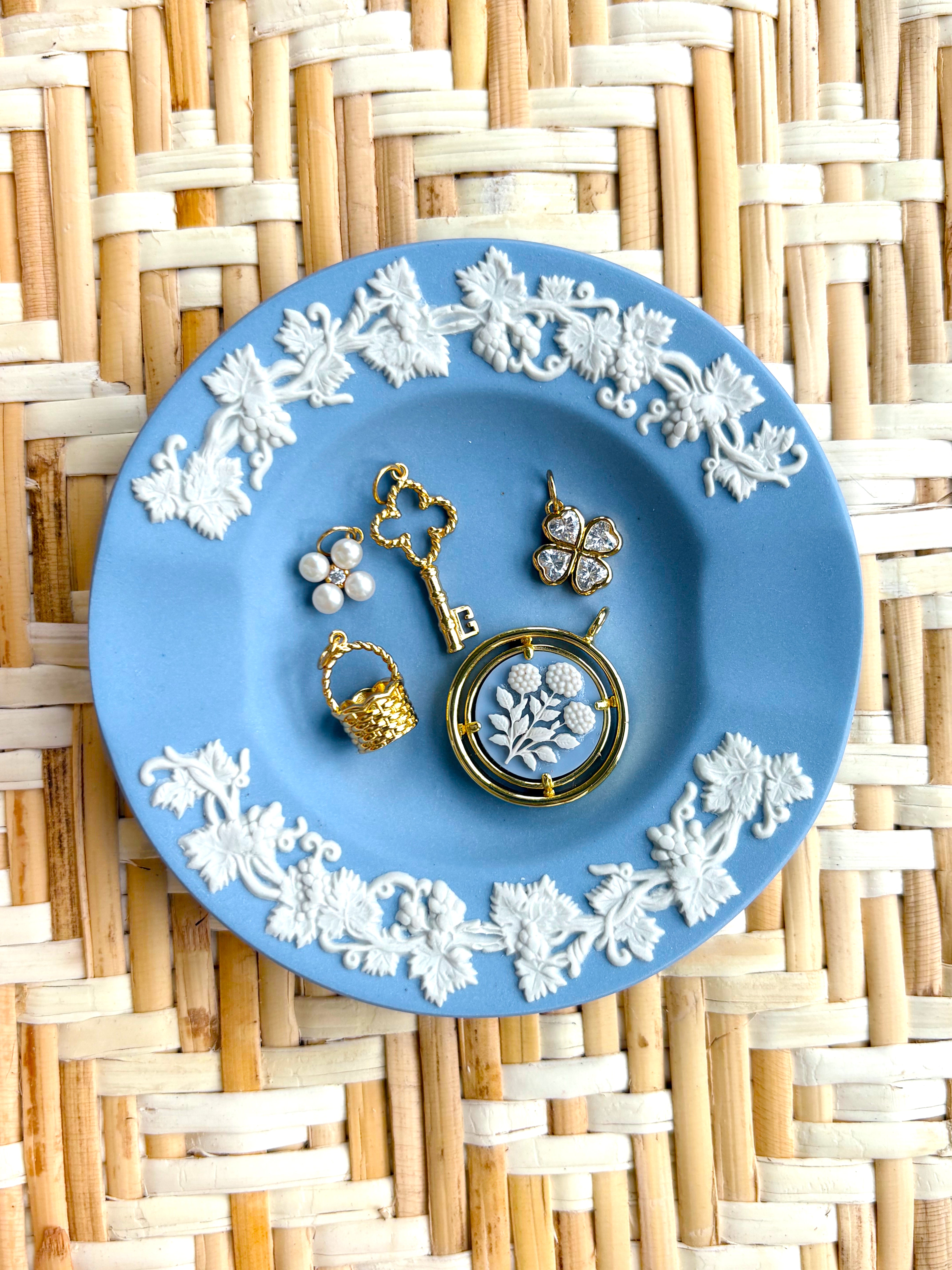 Jewelry set on a blue decorative plate with floral patterns on a woven mat background