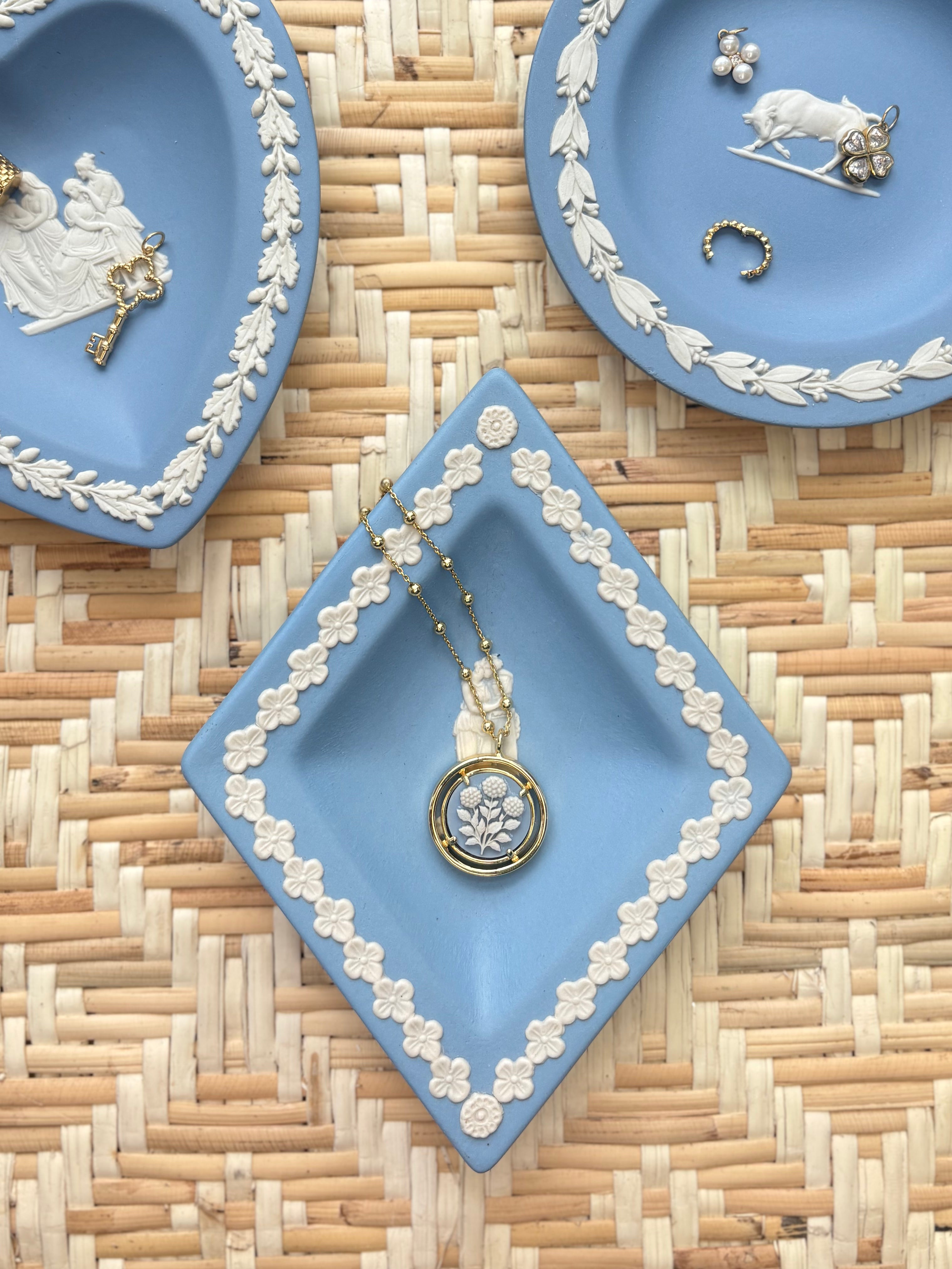 Decorative blue plates with white floral patterns on a woven surface displaying jewelry