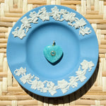 Green heart stone charm on blue plate