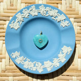 Green heart stone charm on blue plate