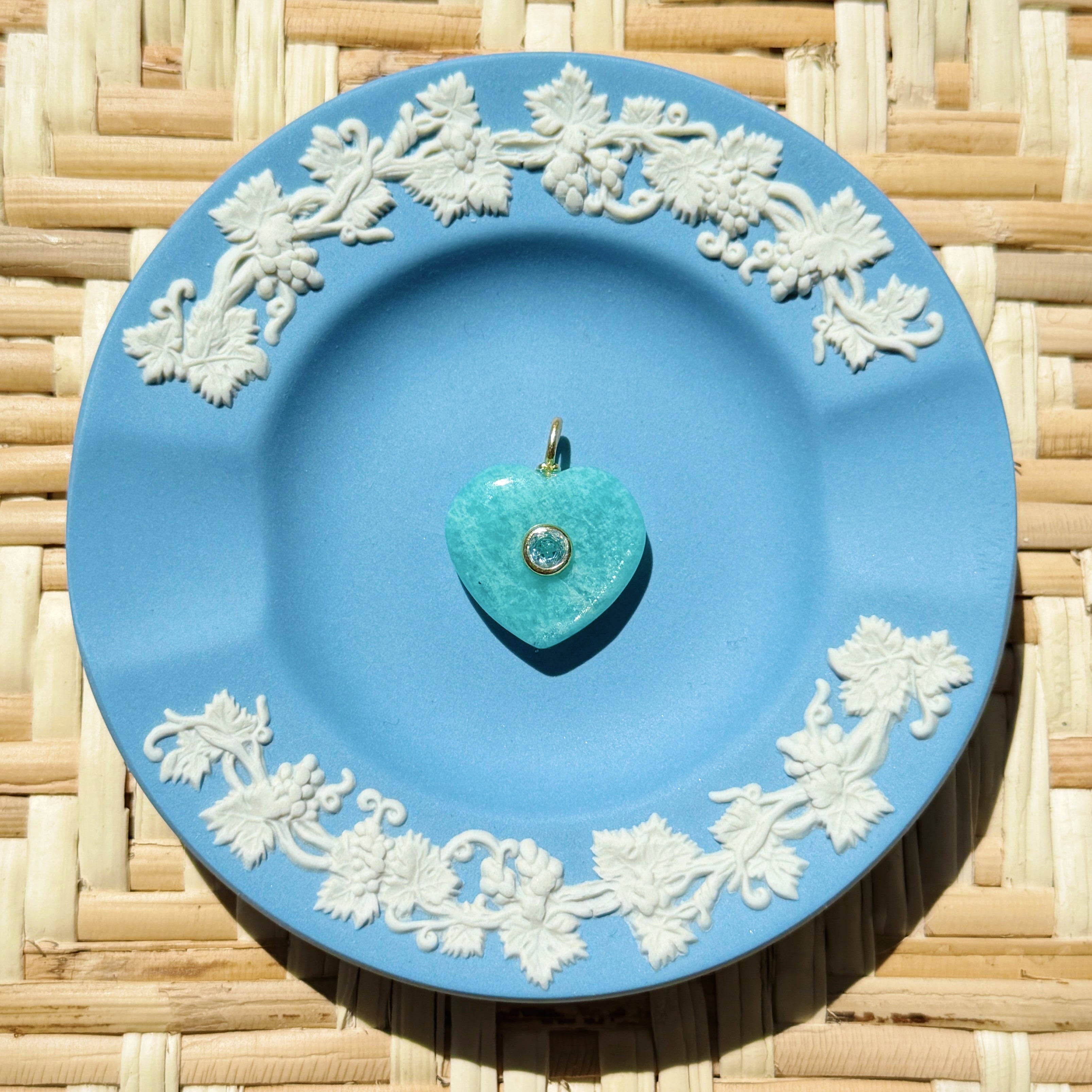 Green heart stone charm on blue plate