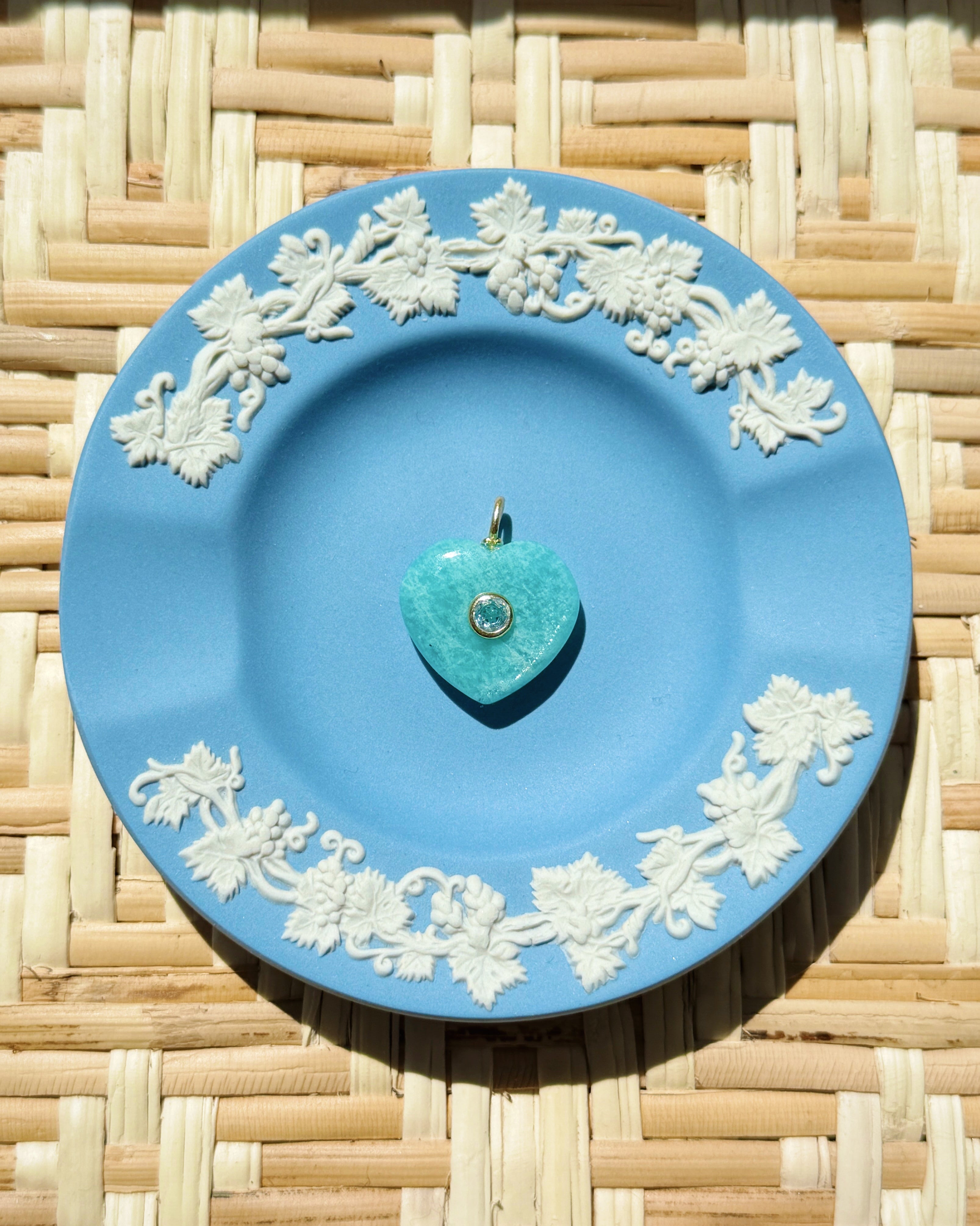 Green heart stone charm on blue plate