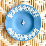 blue plate with a pearl flower charm displayed on a woven background