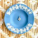 blue plate with a pearl flower charm displayed on a woven background