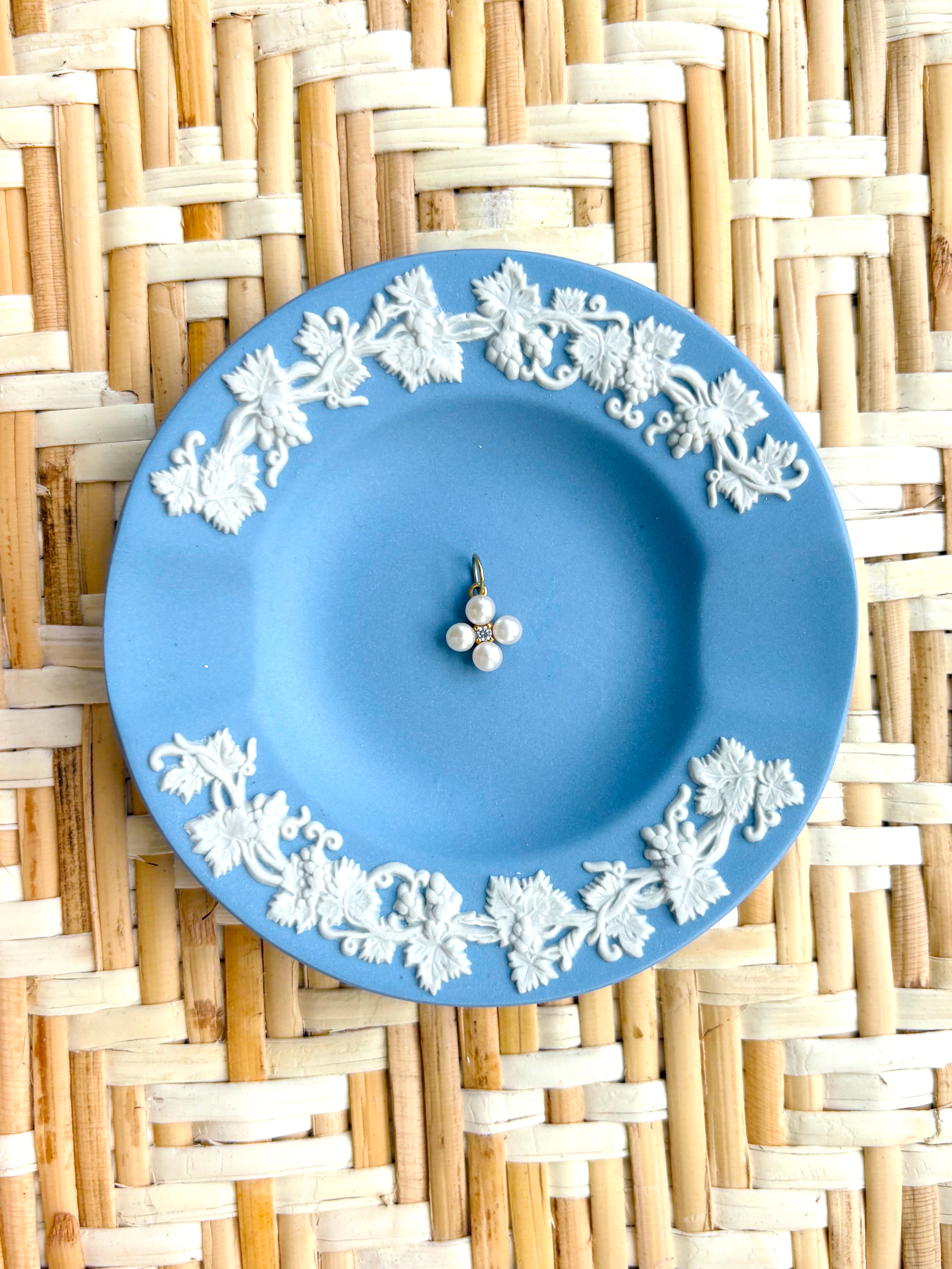 blue plate with a pearl flower charm displayed on a woven background