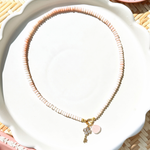 pink opal bead necklace on a white tray with pink decorative dishes