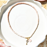 pink opal bead necklace on a white tray with pink decorative dishes