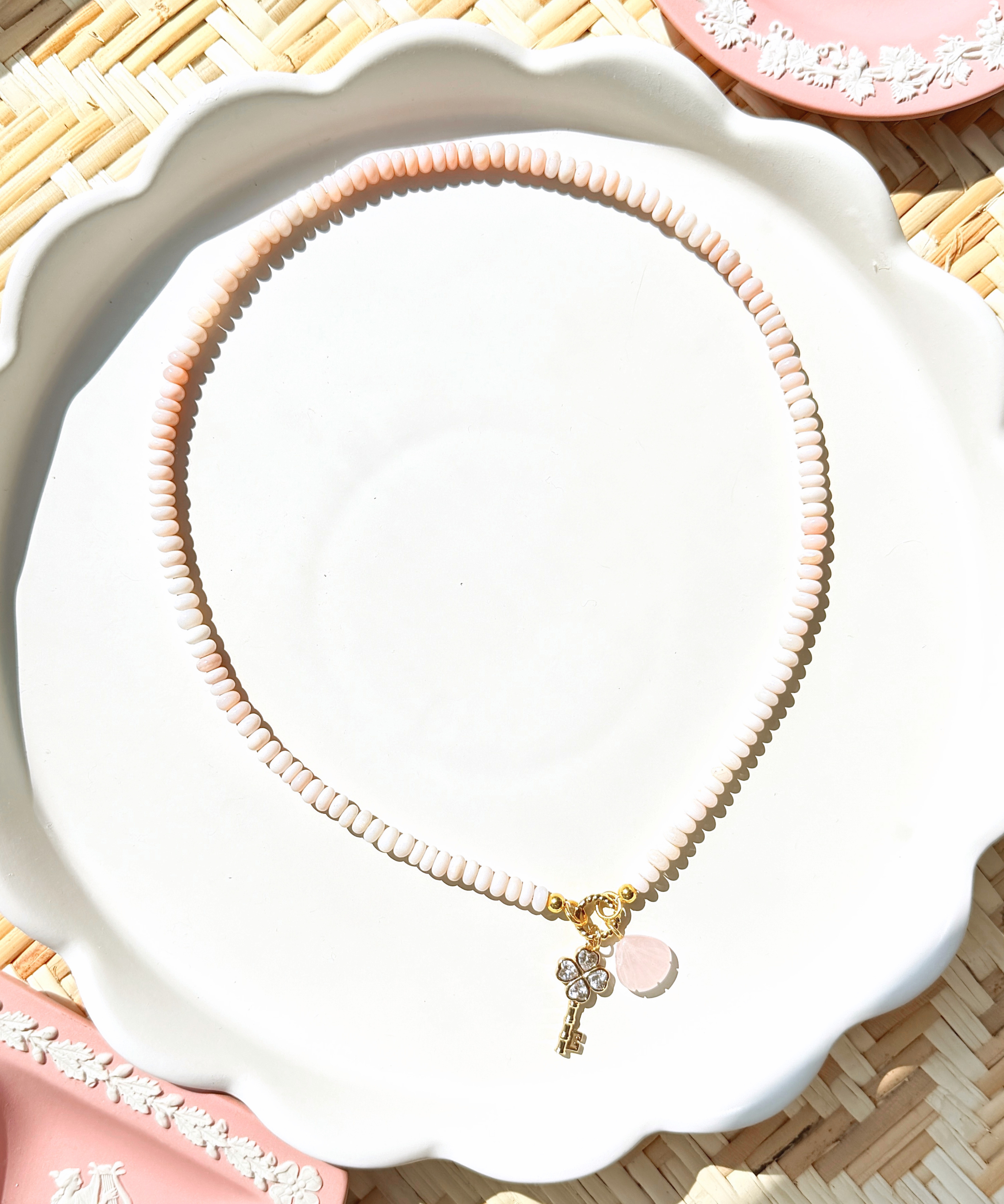 pink opal bead necklace on a white tray with pink decorative dishes