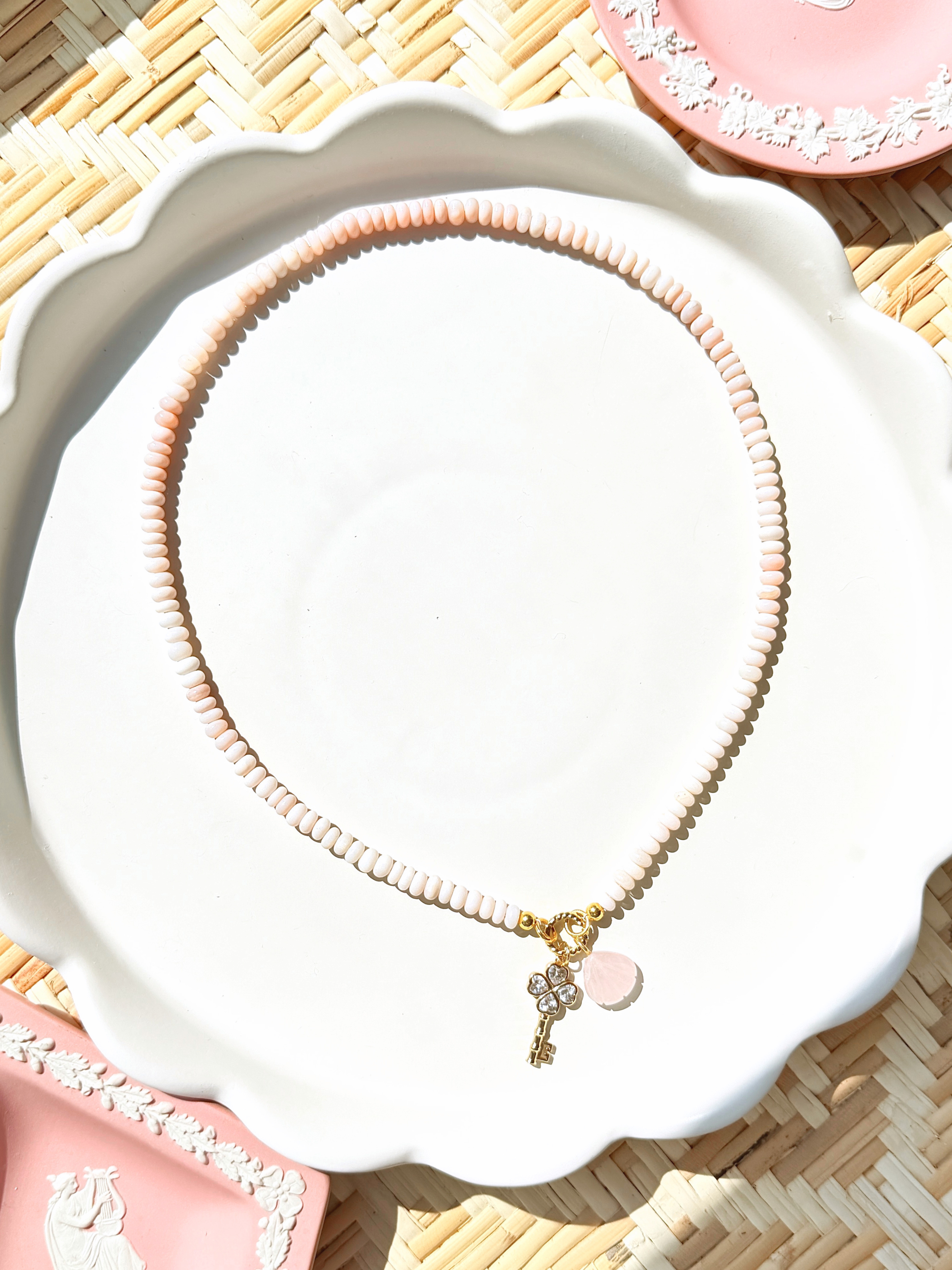 pink opal bead necklace on a white tray with pink decorative dishes