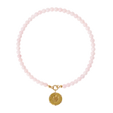 Pink beaded necklace with a gold charm on a white background