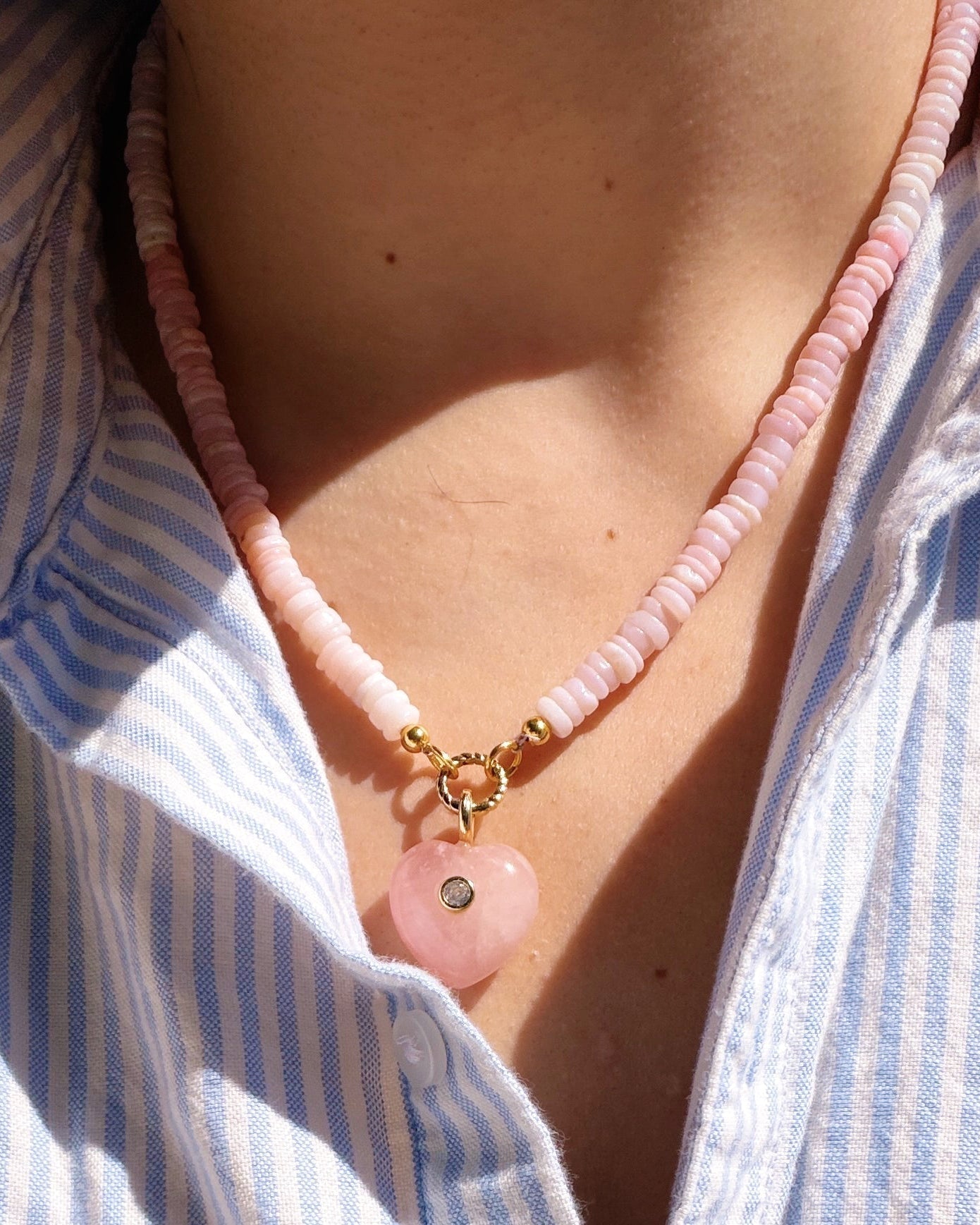 Pink stone heart charm on pink beaded chain on a neck