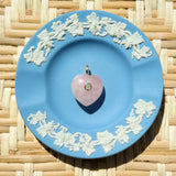 pink rose quartz heart charm on a blue plate