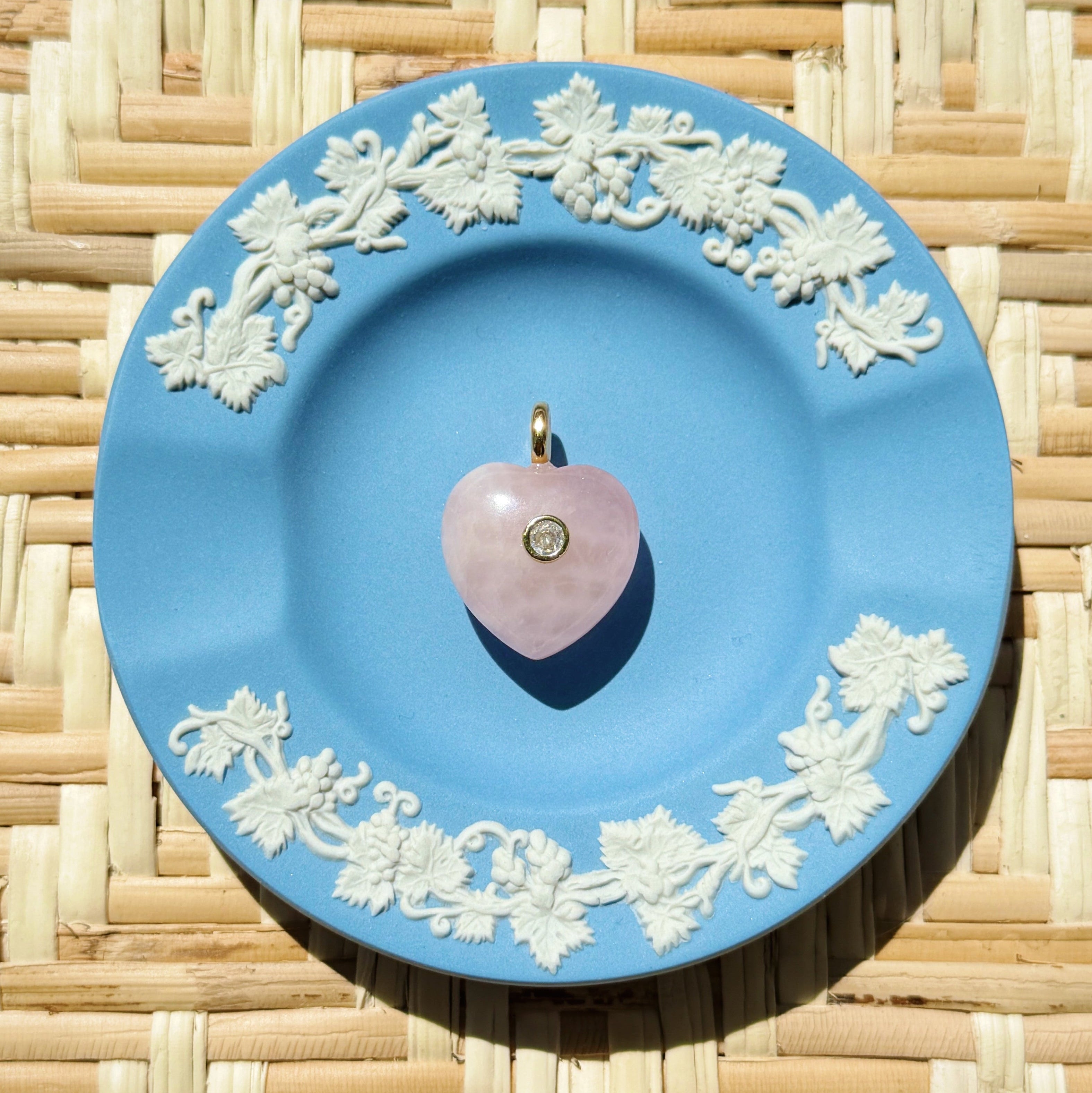 pink rose quartz heart charm on a blue plate