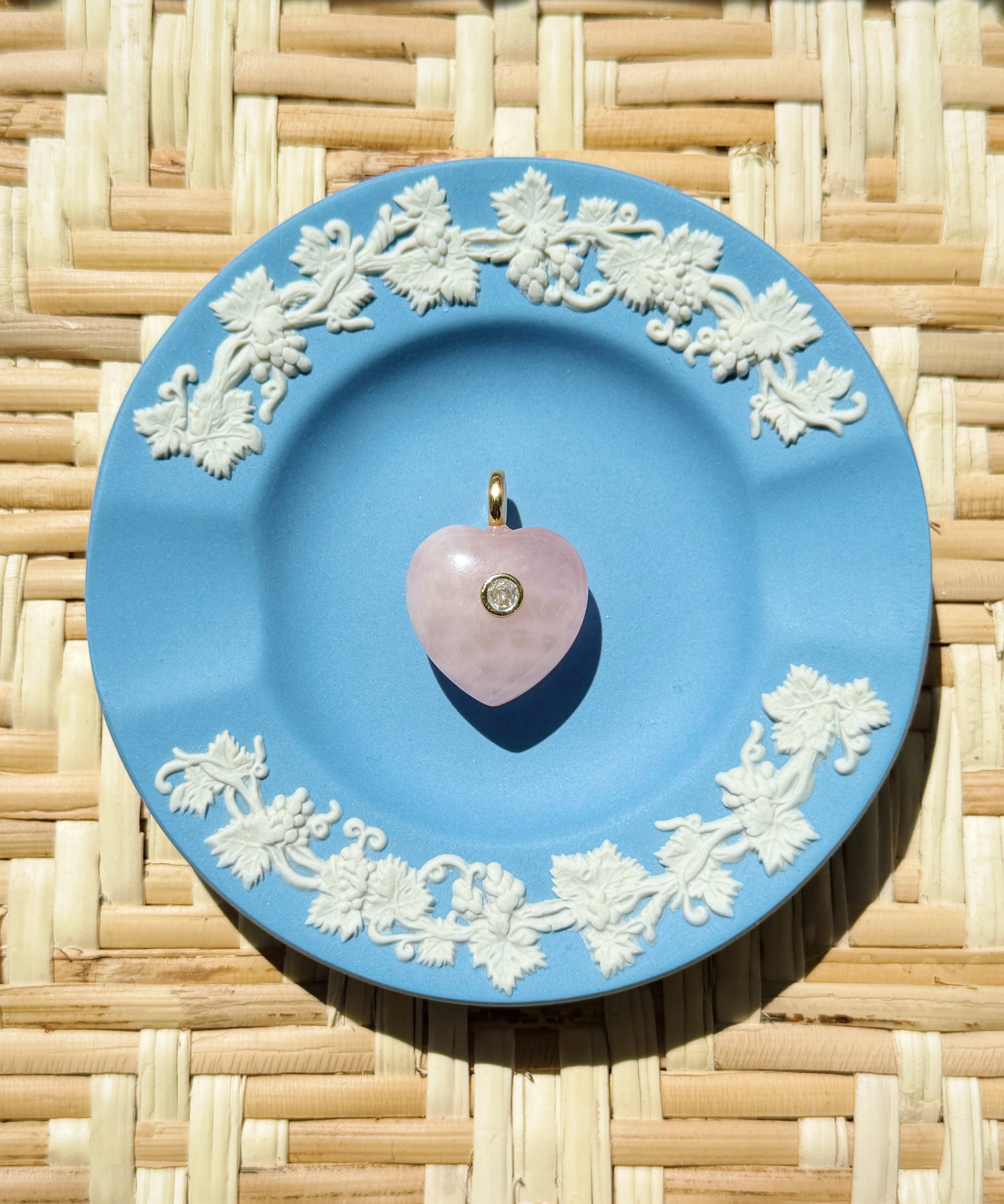 pink rose quartz heart charm on a blue plate