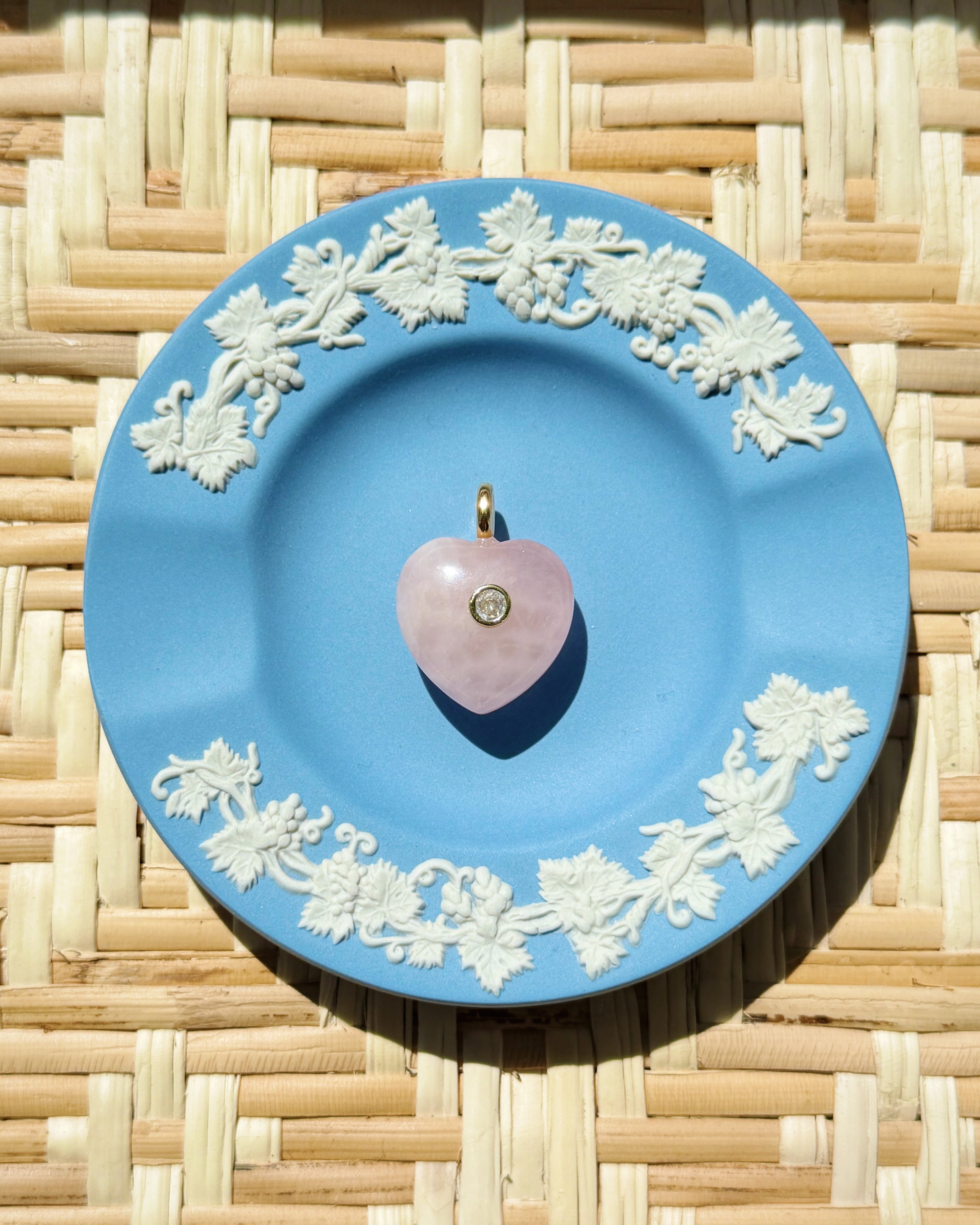 pink rose quartz heart charm on a blue plate