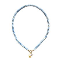Necklace with light blue beads and a gold basket charm and a pearl floral charm on a white background