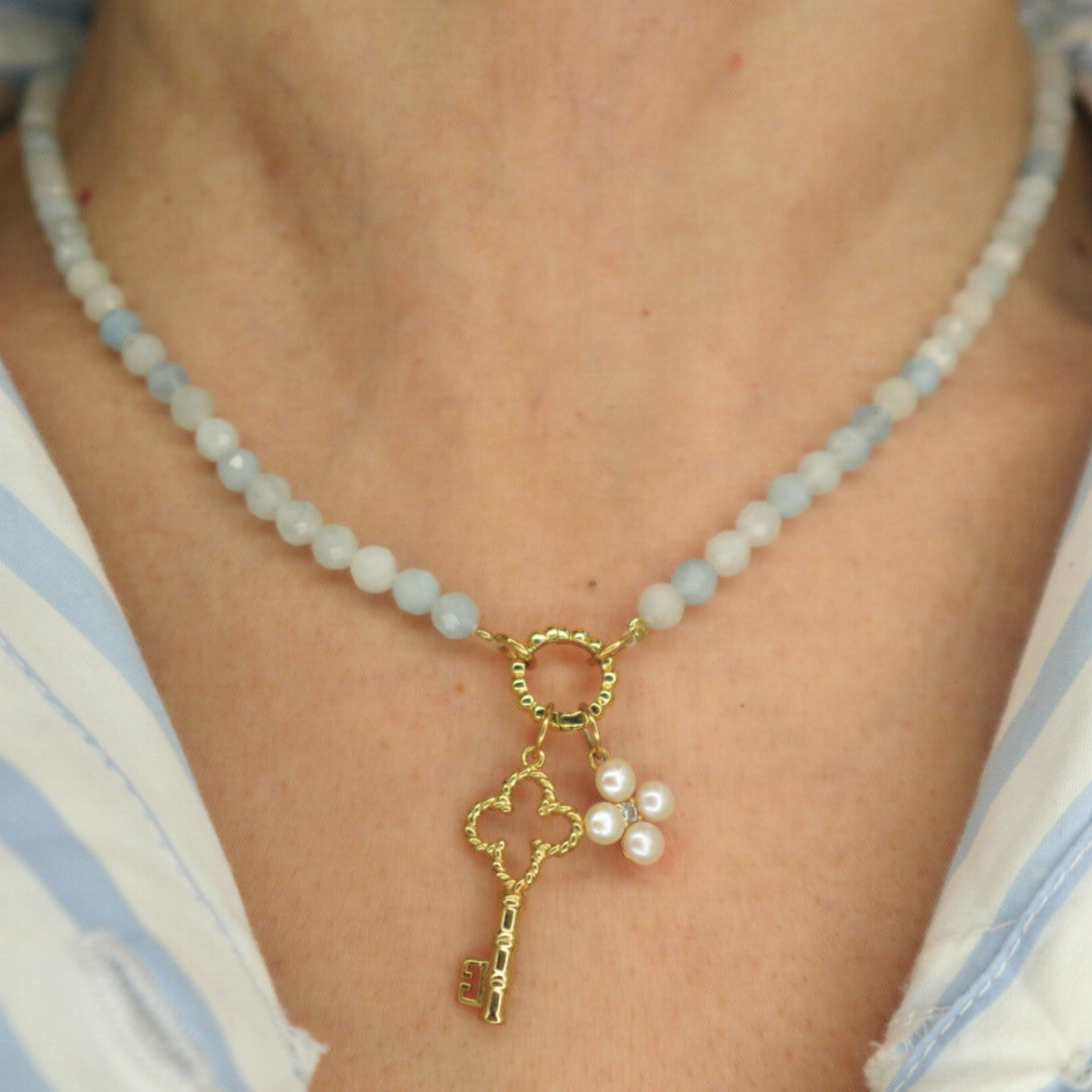 blue beaded necklace with a key charm and pearl flower charm
