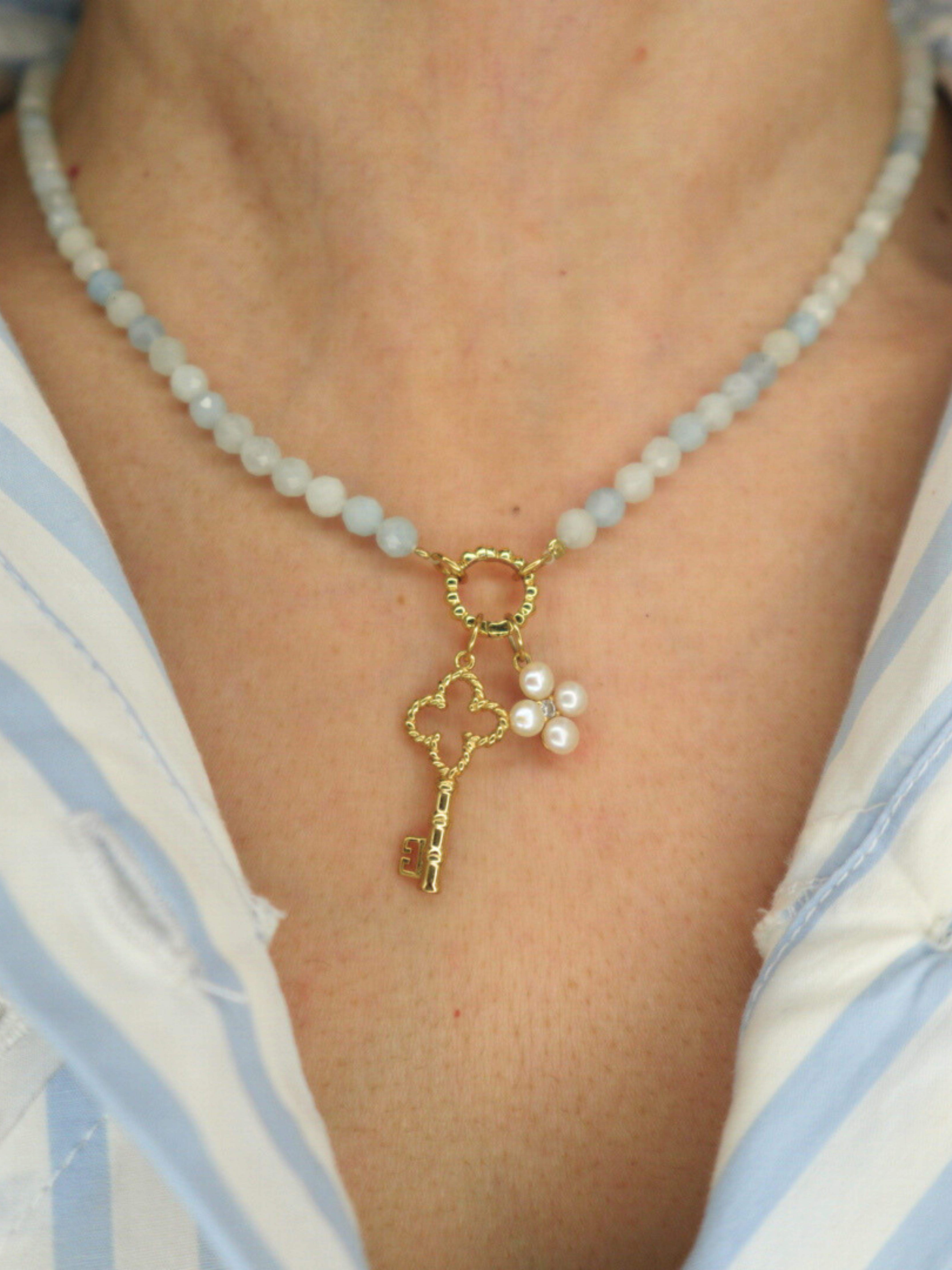 blue beaded necklace with a key charm and pearl flower charm