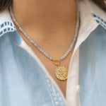 blue beaded necklace with a gold pendant floral charm with blue gemstones