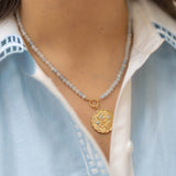 blue beaded necklace with a gold pendant floral charm with blue gemstones